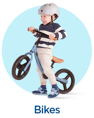 Child riding a blue balance bike wearing a safety helmet.